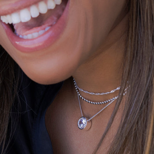 Closeup of woman wearing silver layering jewelry and pendant by Style Dots