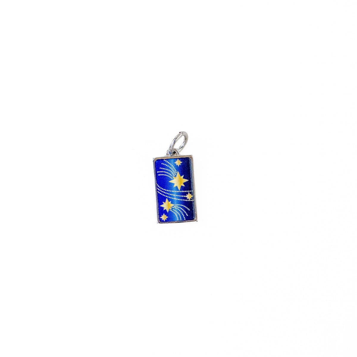 A small rectangular charm pendant with a silver-tone border and loop, featuring a blue enamel background decorated with yellow stars and white swirls, centered on a plain white background.