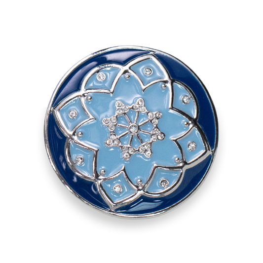 A round enamel pin featuring a detailed lotus flower design in light blue and dark blue, outlined with silver metal and accented with small clear rhinestones.
