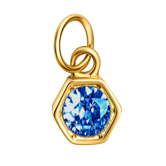 A gold hexagonal pendant charm featuring a faceted blue colored gemstone, isolated on a solid white background.