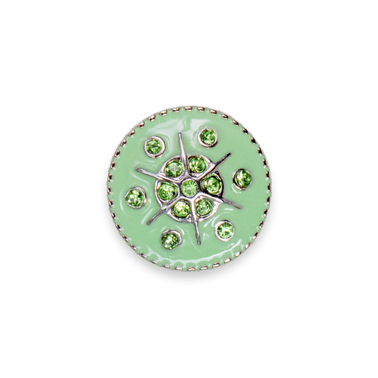 A round light green enamel dot with a silver-tone metal border and a central starburst design set with green faceted rhinestones, shown on a plain white background.