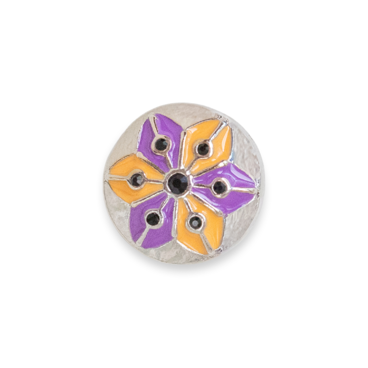 A round silver-toned button featuring a stylized flower design with purple and orange enamel petals and small black dots, set against a plain white background. Release is for Halloween 2026.