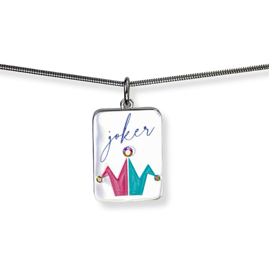 A silver rectangular pendant necklace on a silver snake chain, featuring a white background with a colorful jester crown design in pink and teal, and the word 'joker' written in blue cursive. This Mahjong inspired charm can be shown dangling from the middle of a necklace, but can be used on bracelets and on a charm keeper. 