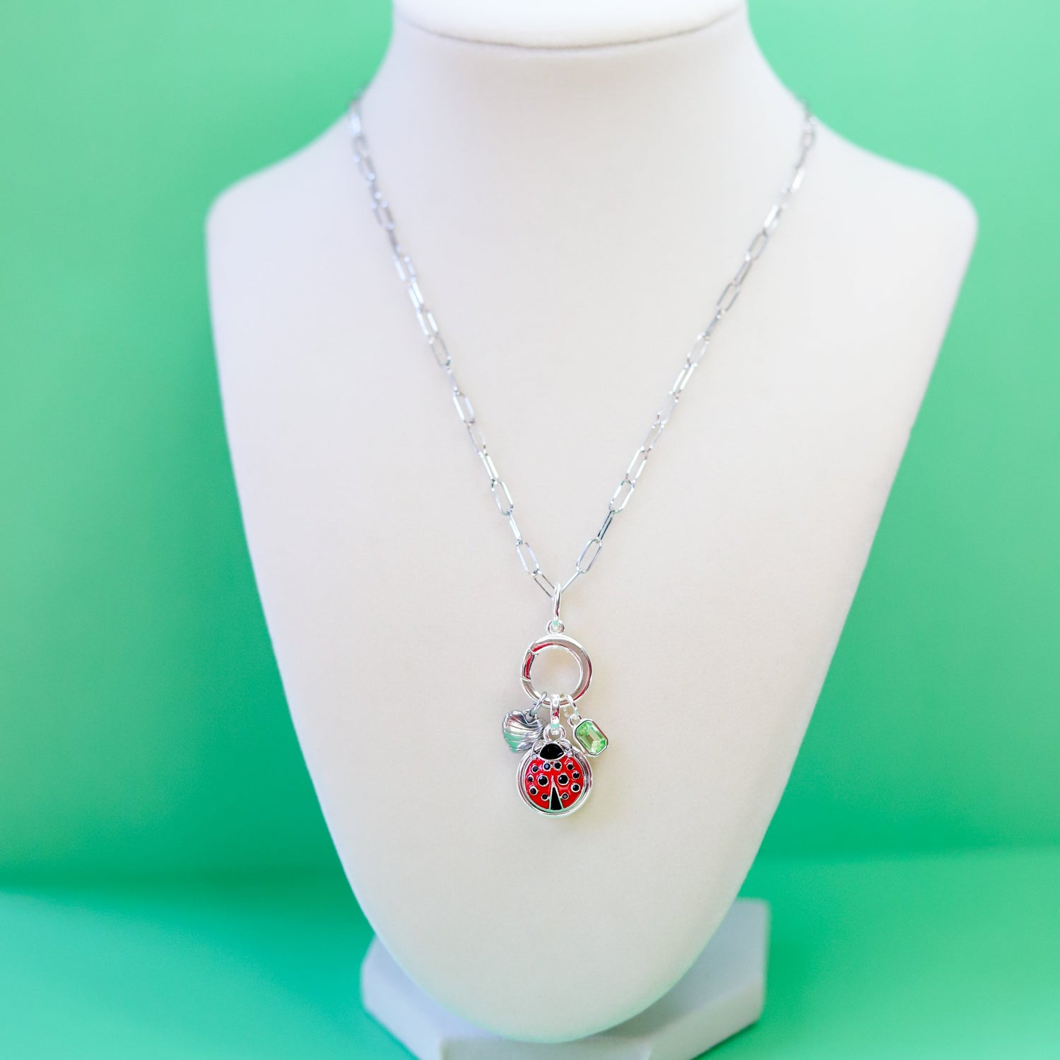 Necklace with a ladybug charm on a mannequin bust against a green background