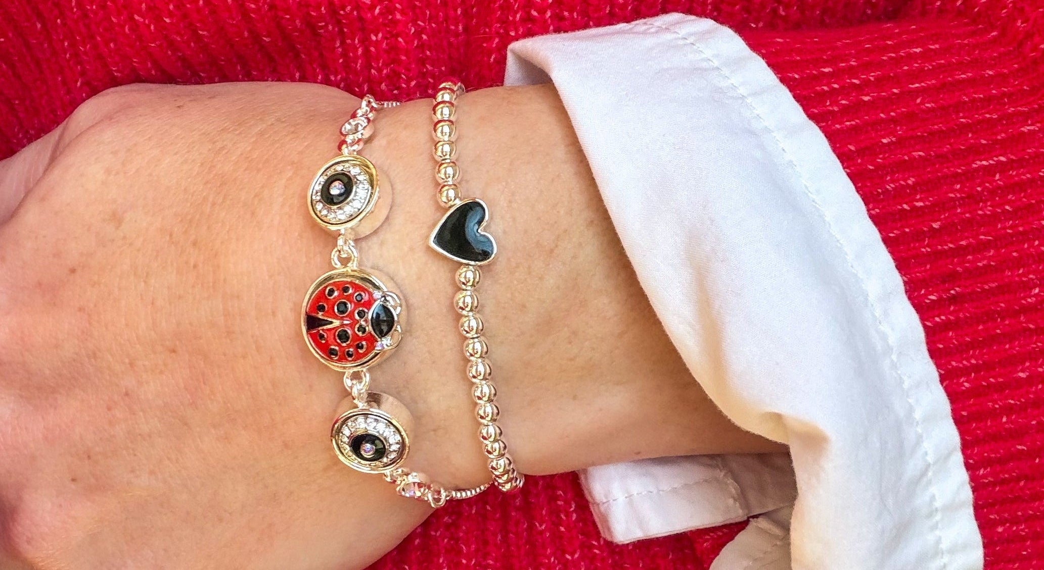 Close-up of a wrist wearing multiple bracelets on a red background