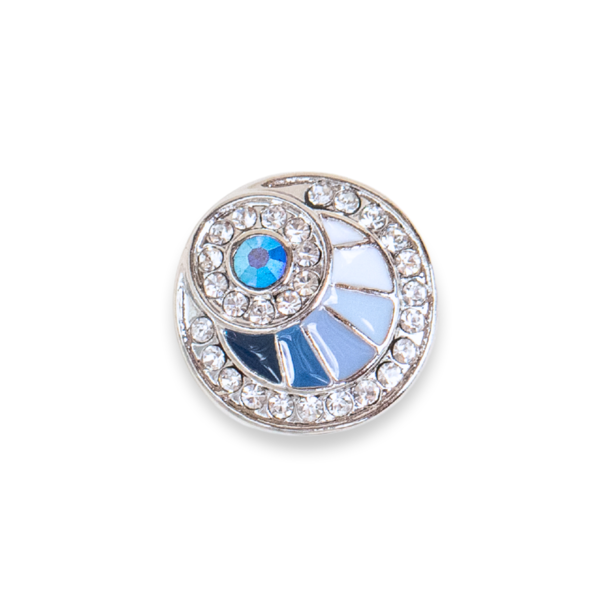 A round silver-toned Dot featuring a halo of clear crystals and a central sunburst design with light blue enamel, a blue iridescent crystal, set against a plain white background. This size is the Original size released in September/ October 2026