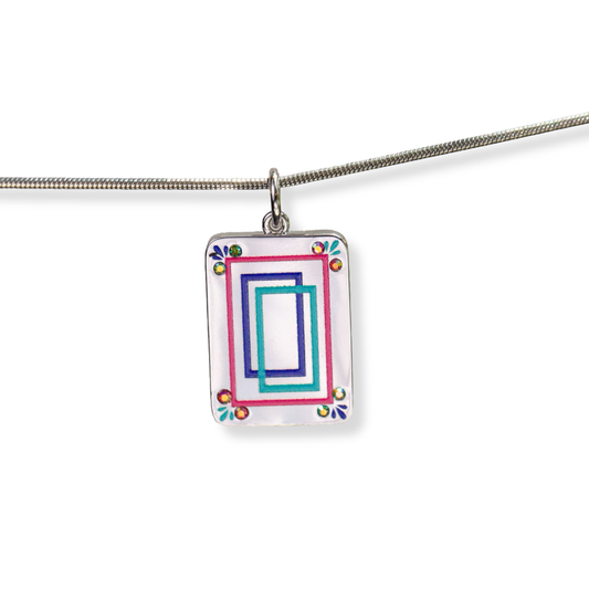 A silver rectangular pendant necklace featuring a colorful geometric design with nested pink, blue, and teal rectangles on a white background, suspended from a silver snake chain.
